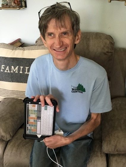 James smiling and holding iPad with the Verbally App on it's screen