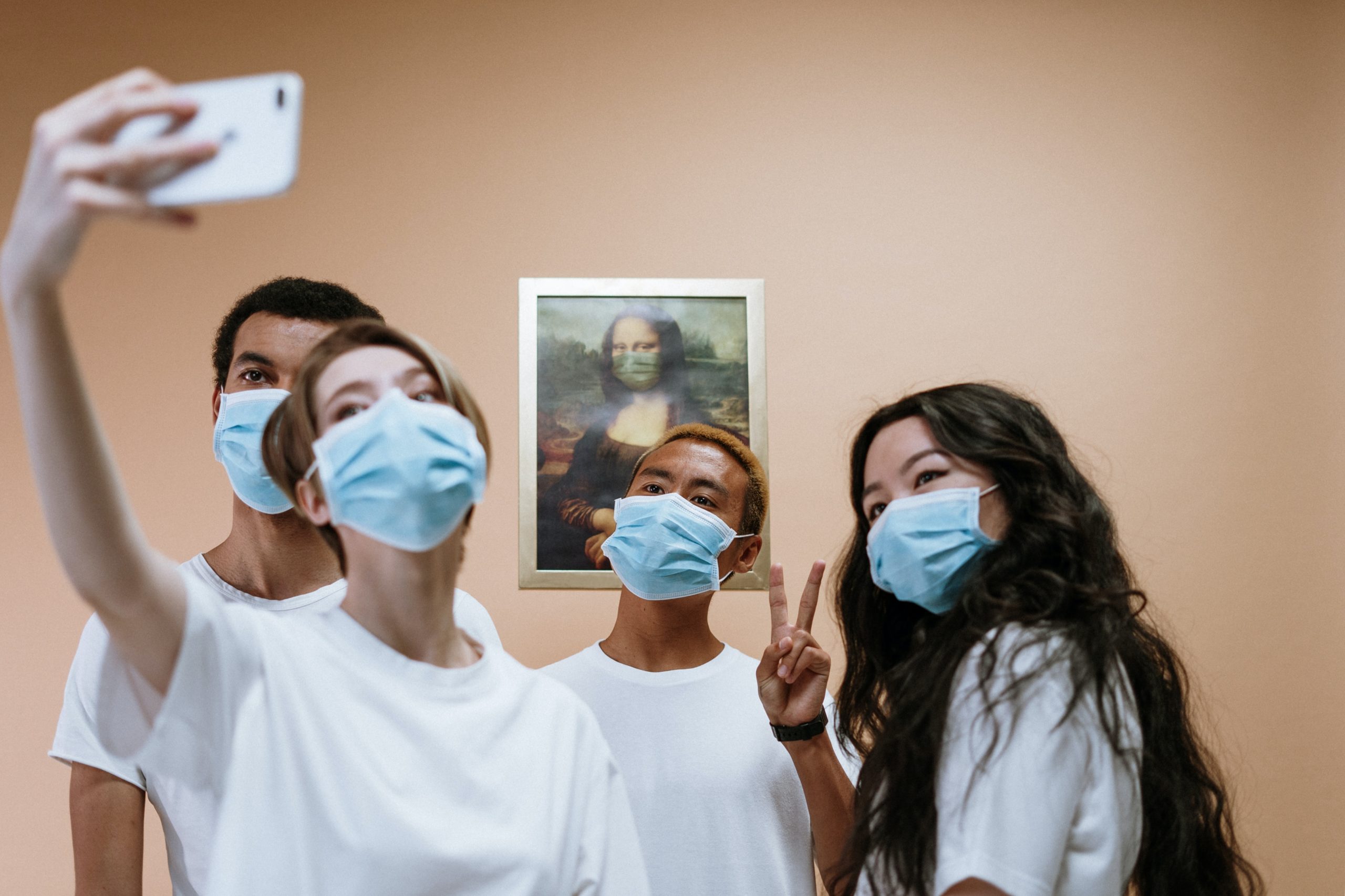 group-of-people-taking-a-group-selfie-3957989-scaled 4 people wearing masks take a selfie in front of a painting of the Mona Lisa; the Mona Lisa is wearing a mask too!