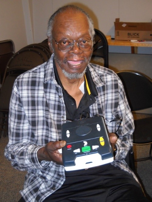 Mark smiling while holding up the book reader machine