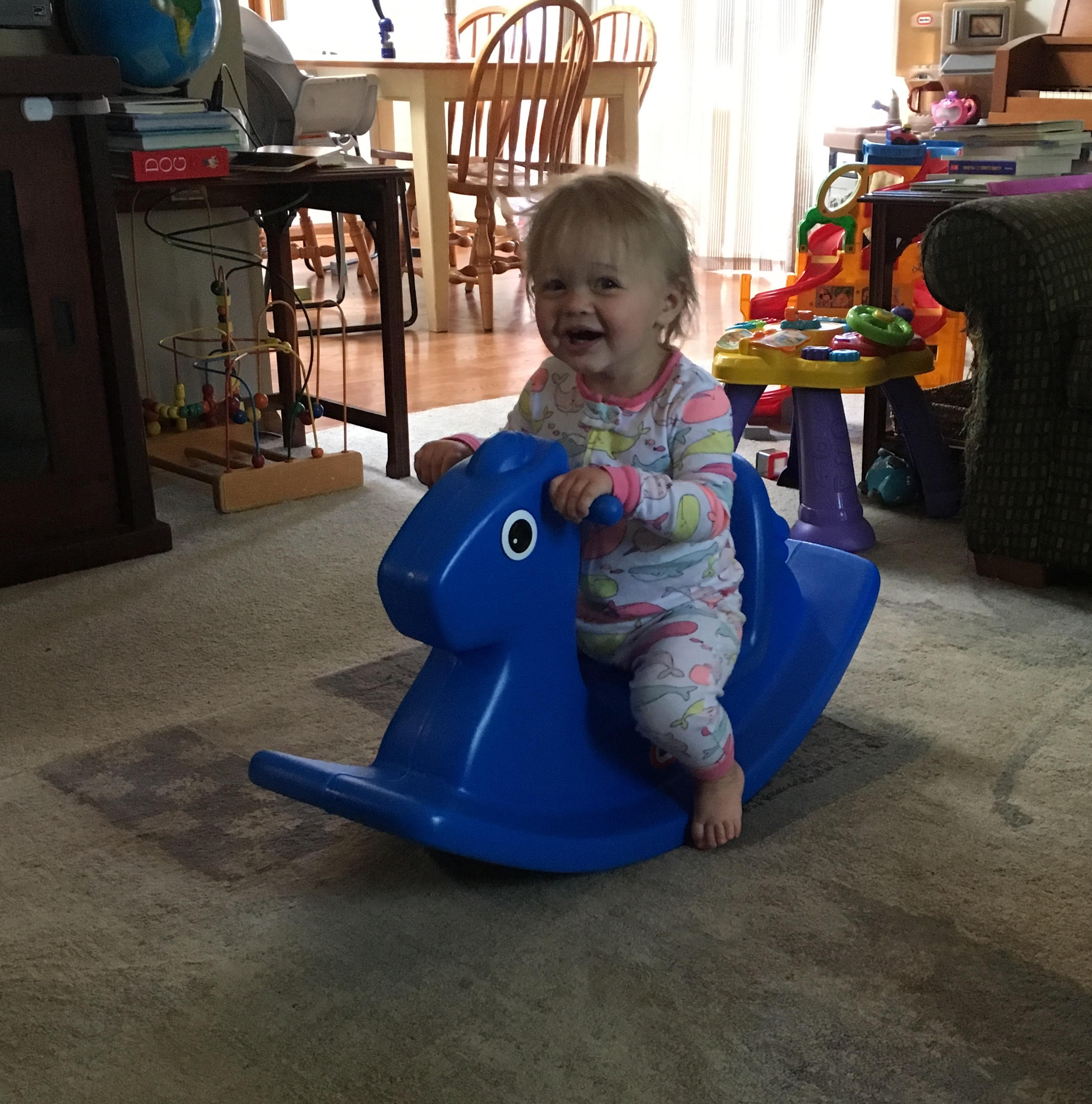 rocking horse a toddler on a rocking horse with toys in the background